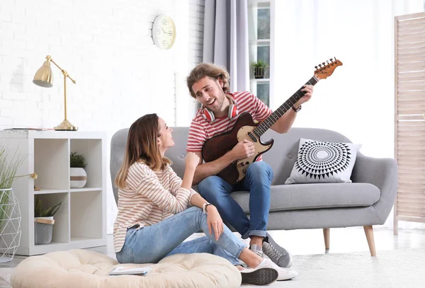 Joven tocando la guitarra eléctrica para su novia en el salón — Foto de Stock