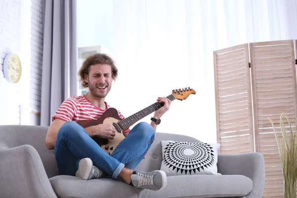 Jonge man spelen gitaar in de woonkamer. Ruimte voor tekst — Stockfoto