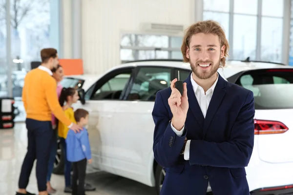 Vendedor de carro com chave e família turva perto de auto no fundo — Fotografia de Stock