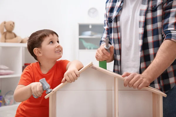 Mannen och hans barn som leker byggare med trä docka hus hemma — Stockfoto
