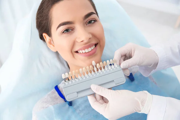 Dentista selecionando a cor dos dentes do paciente com paleta na clínica — Fotografia de Stock