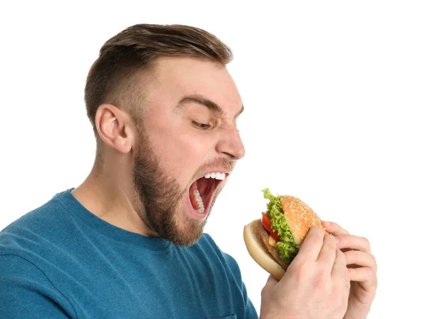 Jovem comendo hambúrguer saboroso no fundo branco — Fotografia de Stock