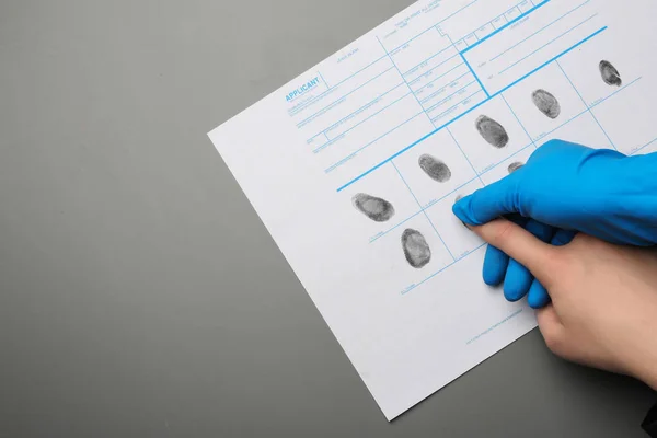 Investigator taking fingerprints of suspect on grey background, top view with space for text. Criminal expertise — Stock Photo, Image