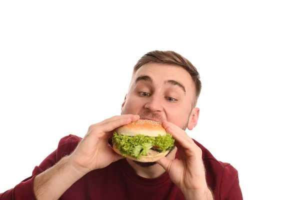 Young man eating tasty burger on white background — Stock Photo, Image