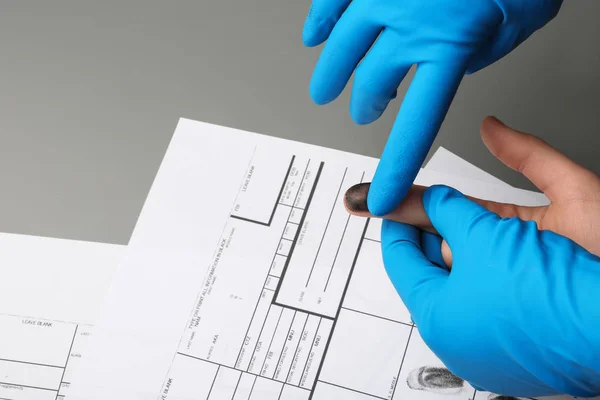 Onderzoeker voor het nemen van vingerafdrukken van verdachte aan tafel, close-up. Criminele expertise — Stockfoto