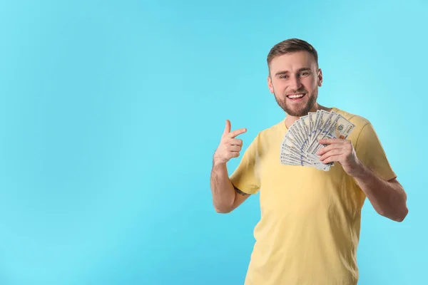 Portrait of happy young man with money on color background. Space for text — Stock Photo, Image