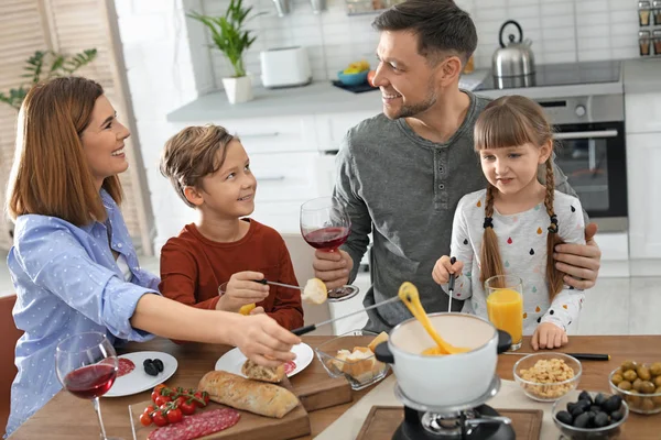 Família feliz desfrutando de jantar fondue em casa — Fotografia de Stock