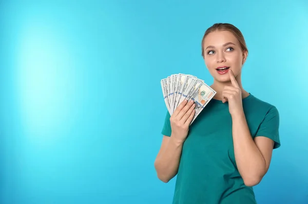 Portrait of thoughtful young woman with money on color background. Space for text — Stock Photo, Image