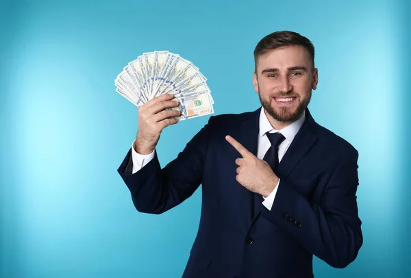 Portrait of happy young businessman with money on color background — Stock Photo, Image