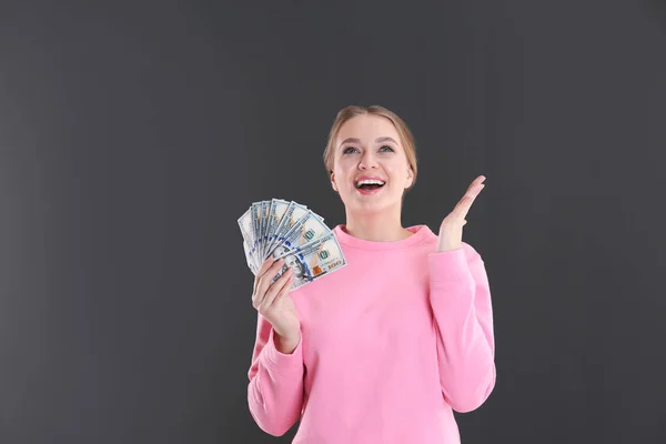 Ritratto di giovane donna emotiva con soldi su sfondo grigio — Foto Stock