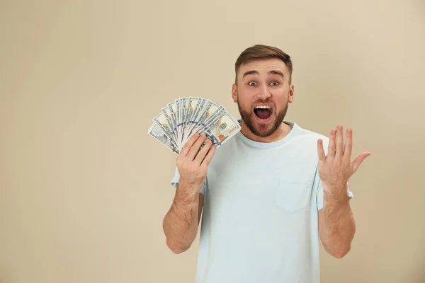 Portrait of emotional young man with money on color background. Space for text — Stock Photo, Image