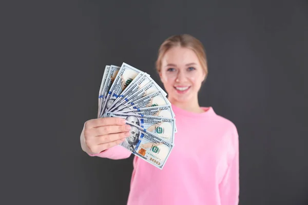 Portret van gelukkige jonge vrouw met geld op de grijze achtergrond — Stockfoto