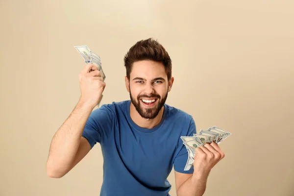 Portrait of happy young man with money on color background — Stock Photo, Image