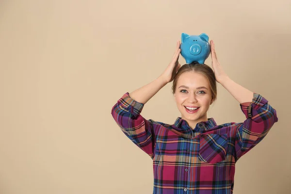 Mujer joven feliz con alcancía y espacio para el texto sobre fondo de color. Ahorro de dinero —  Fotos de Stock