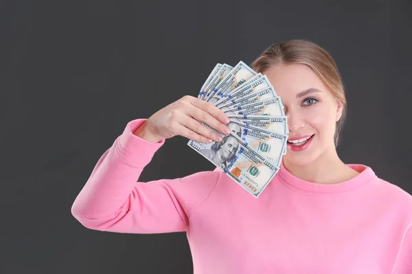 Portrét šťastná mladá žena s penězi na šedém pozadí — Stock fotografie
