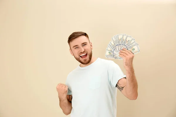Portrait of emotional young man with money on color background — Stock Photo, Image