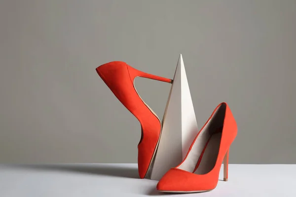 Samenstelling met elegante vrouwelijke schoenen op tafel tegen de grijze achtergrond — Stockfoto