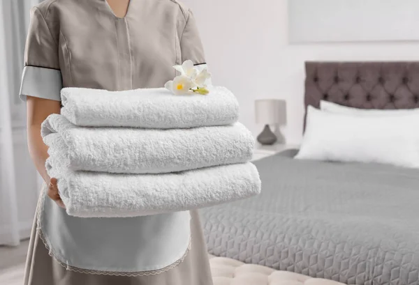 Maid holding fresh towels with flowers in hotel room, closeup — Stock Photo, Image