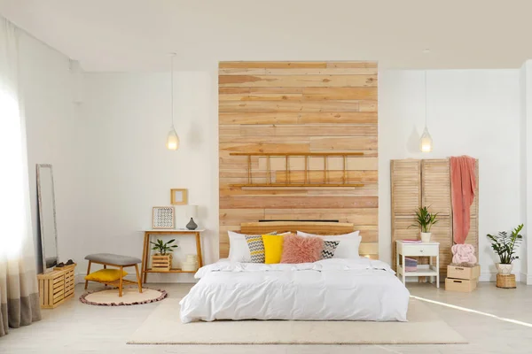 Stylowe wnętrze i wygodne łóżko, blisko ściany drewniane — Zdjęcie stockowe