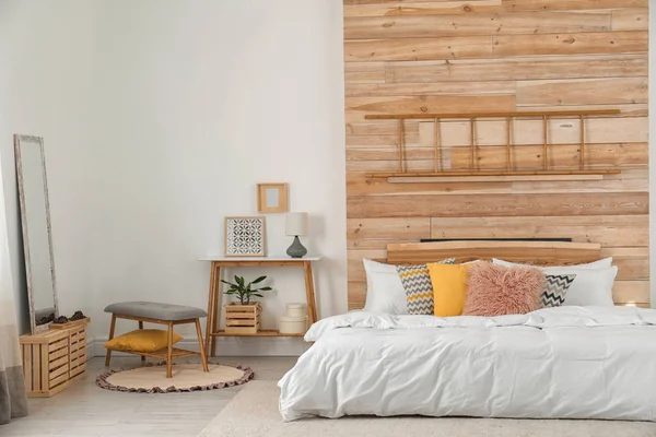Quarto elegante interior com cama confortável perto da parede de madeira — Fotografia de Stock