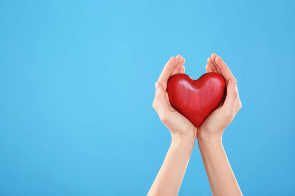 Женщина держит в руках декоративное сердце на цветном фоне, пространство для текста
