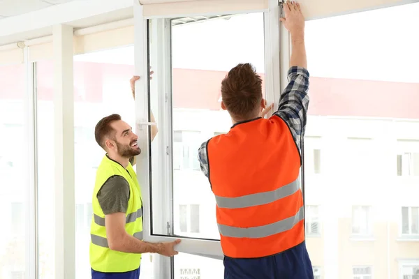 Trabalhadores da construção instalando janela de plástico em casa — Fotografia de Stock