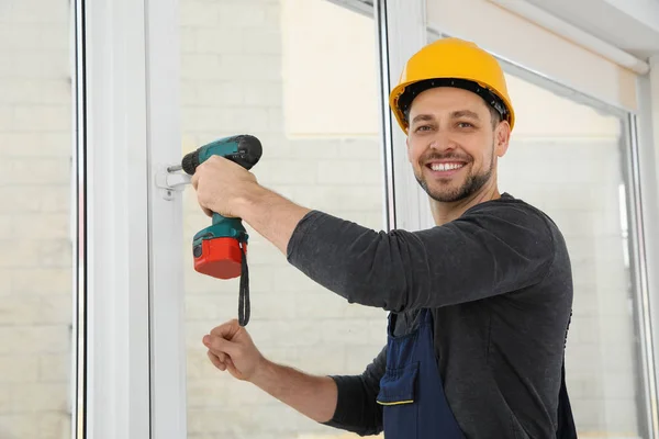 Trabajador de la construcción usando taladro mientras instala ventana en interiores — Foto de Stock