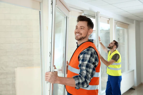 Trabajadores de la construcción instalando ventanas de plástico en casa —  Fotos de Stock