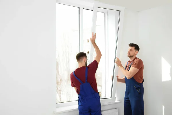 Bauarbeiter montieren Kunststofffenster in Haus — Stockfoto