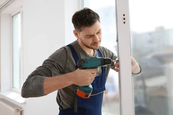 Byggnadsarbetare med borren medan du installerar fönster inomhus — Stockfoto