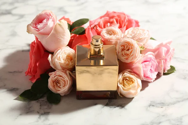 Μπουκάλι άρωμα με όμορφα τριαντάφυλλα σε μαρμάρινο φόντο — Φωτογραφία Αρχείου