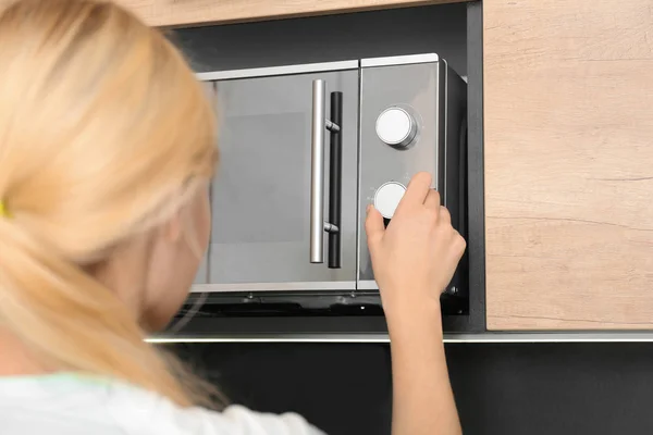 Jonge vrouw moderne magnetron in de keuken, close-up aanpassen — Stockfoto