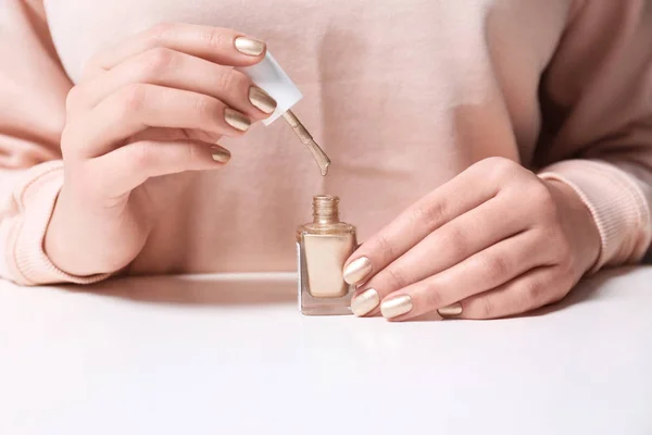 Mujer con botella de esmalte de uñas en la mesa, primer plano —  Fotos de Stock