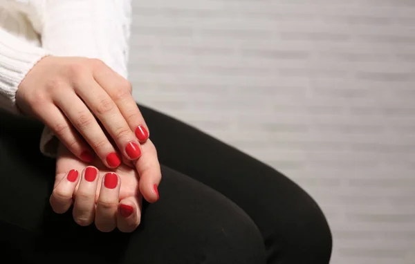 Женщина с красным маникюром на размытом фоне, место для текста. Тенденции лака для ногтей — стоковое фото