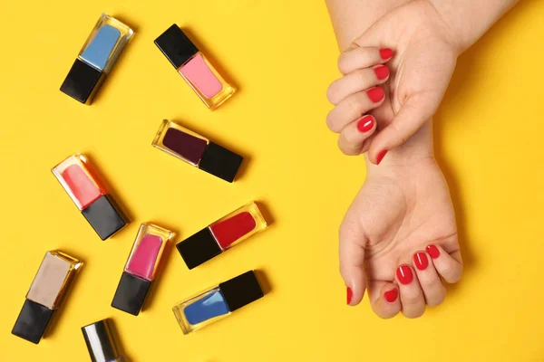 Woman with red manicure and nail polish bottles on color background, top view — Stock Photo, Image