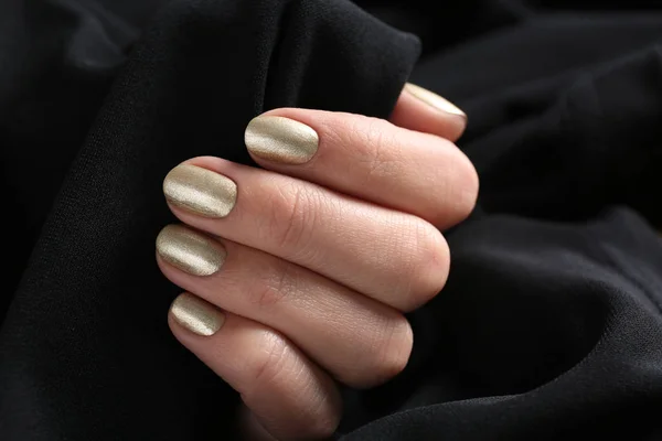 Mujer con manicura dorada sosteniendo tela negra, primer plano. Tendencias de esmalte de uñas —  Fotos de Stock
