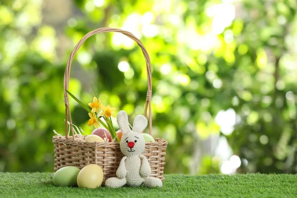 可爱的复活节兔子玩具与柳条篮和染色鸡蛋在绿草如茵的背景下, 文本的空间 — 图库照片