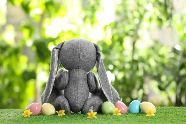 可爱的复活节兔子玩具和染色鸡蛋在绿色的草地上模糊的背景, 文本的空间 — 图库照片