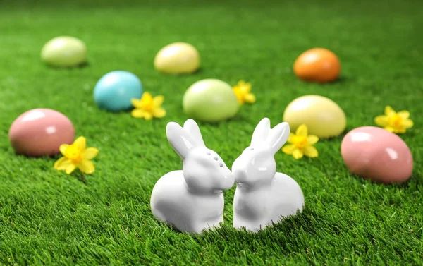 绿色草地上的陶瓷复活节兔子和染色蛋 — 图库照片