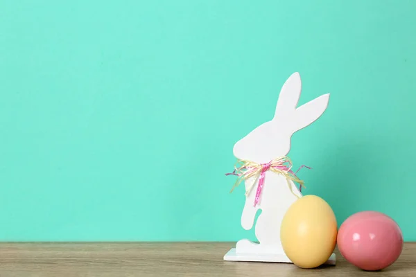 可爱的木制复活节兔子和染色鸡蛋在桌子上的颜色背景, 文本的空间 — 图库照片