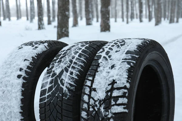 Novos pneus de inverno cobertos de neve perto da floresta, close-up — Fotografia de Stock