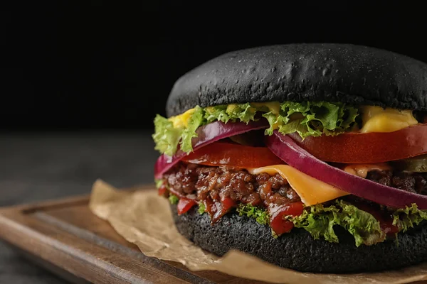 Διοικητικό Συμβούλιο με μαύρο burger σε σκούρο φόντο, κινηματογράφηση σε πρώτο πλάνο. Χώρο για το κείμενο — Φωτογραφία Αρχείου