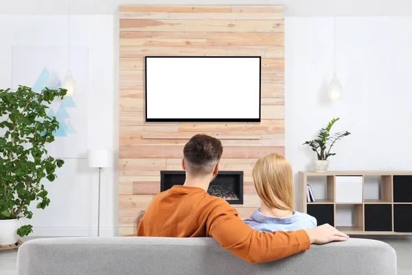 Paar tv-kijken op de bank in de woonkamer met decoratieve open haard — Stockfoto
