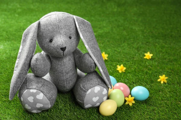 可爱的复活节兔子玩具和染色鸡蛋上的绿草, 文字空间 — 图库照片