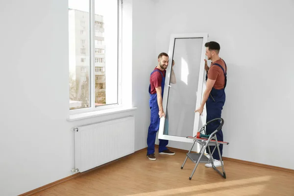 Construction workers installing plastic window in house — Stock Image Construction workers installing plastic window in house Stock Picture