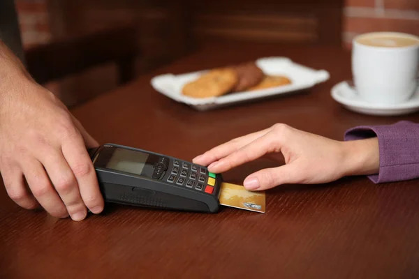 Mujer usando terminal para pago con tarjeta de crédito en cafetería, primer plano — Foto de Stock