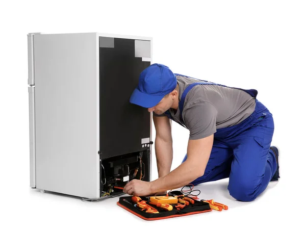 Técnico masculino en uniforme reparando refrigerador sobre fondo blanco — Foto de Stock