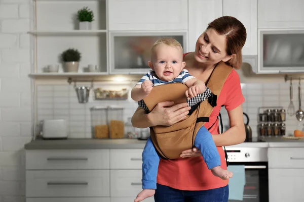 Femme avec son fils dans le porte-bébé à la maison. Espace pour le texte — Photo