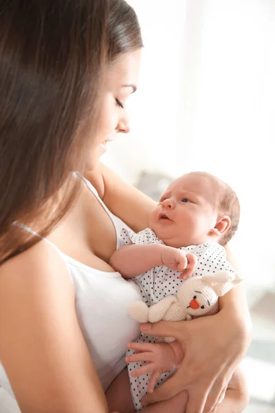 Junge Frau mit ihrem neugeborenen Baby auf verschwommenem Hintergrund — Stockfoto