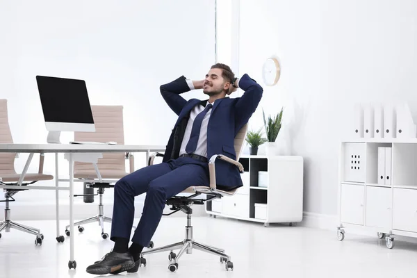 Jovem empresário sentado em cadeira de escritório no local de trabalho — Fotografia de Stock